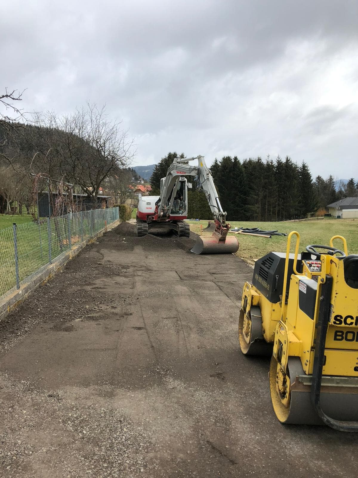 Minibagger und Walze bei Verdichtungsarbeiten